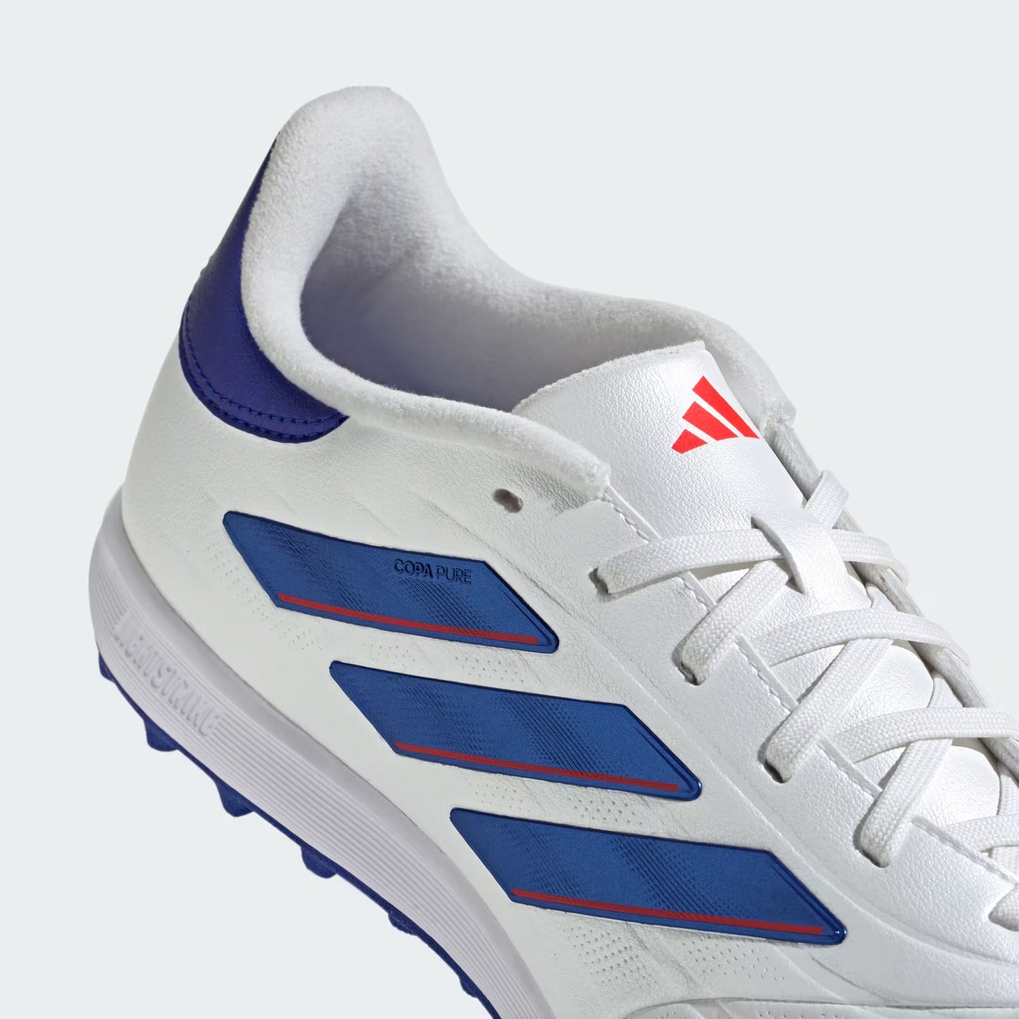 White sports shoe with blue accents and a red logo on a light gray background