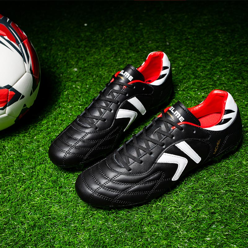 Kelme Black soccer shoes with red accents on a grass field