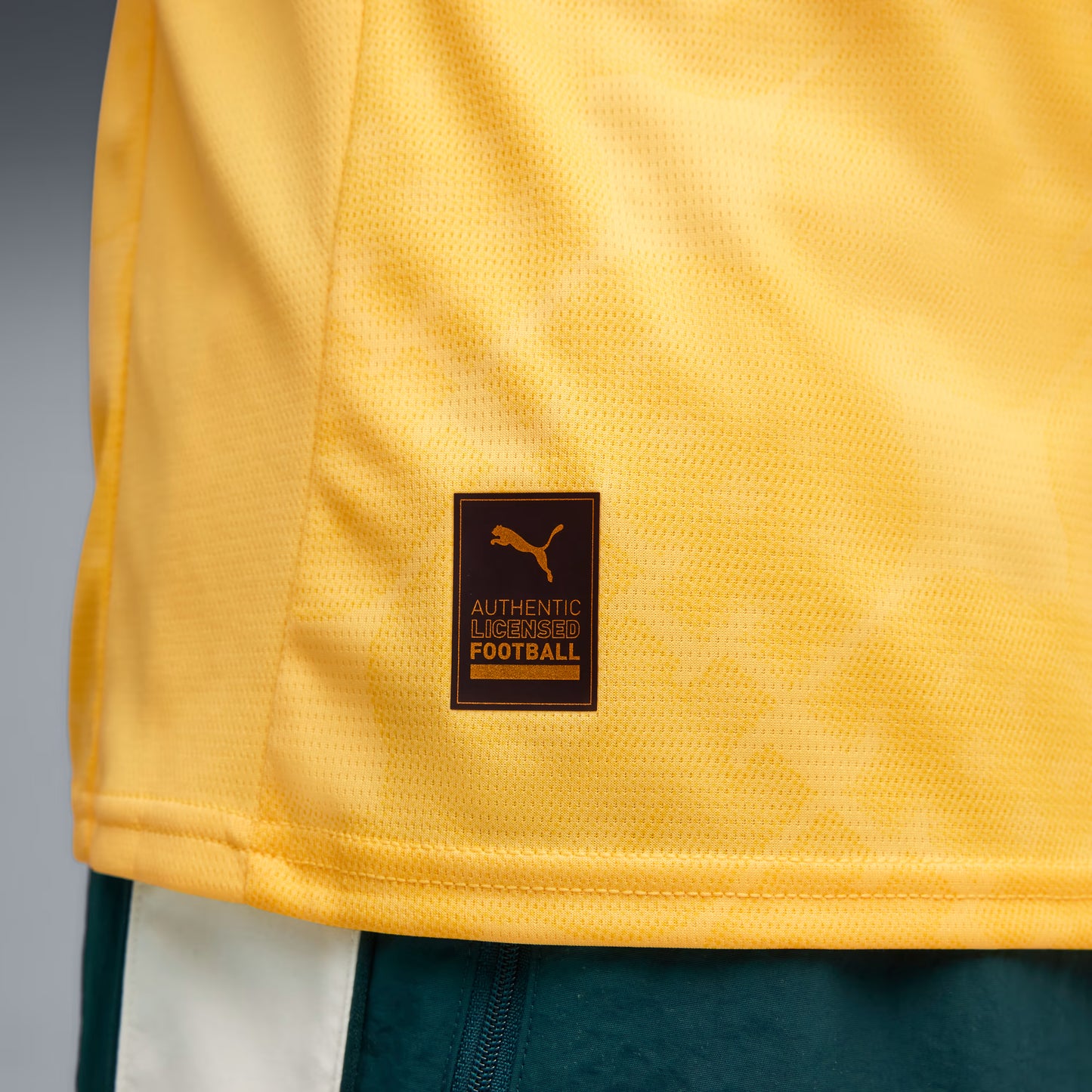 Close-up of a yellow sports jersey with a brand logo on a gray background
