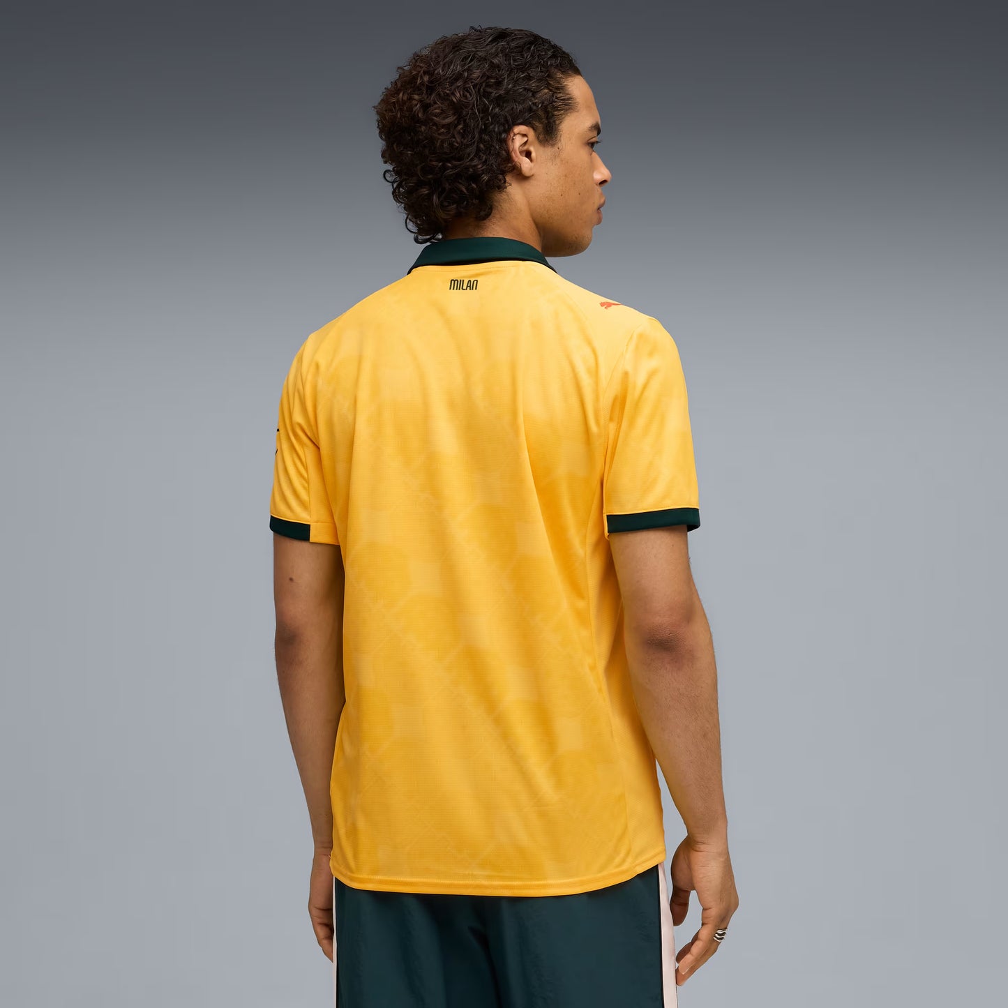 Person wearing a yellow sports jersey with green accents on a gray background