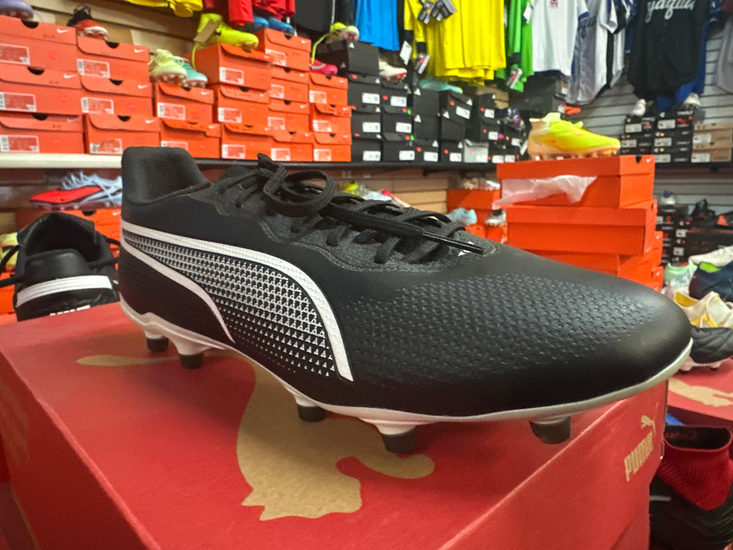 Black soccer cleat on a red box with a store background