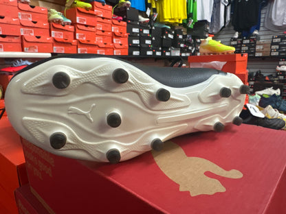 White soccer cleat with black studs on a red display box in a store setting