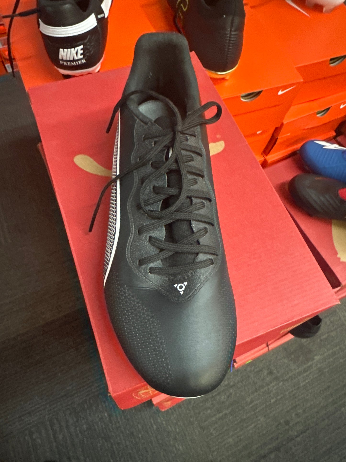 Black athletic shoe on a red box with other shoes in the background