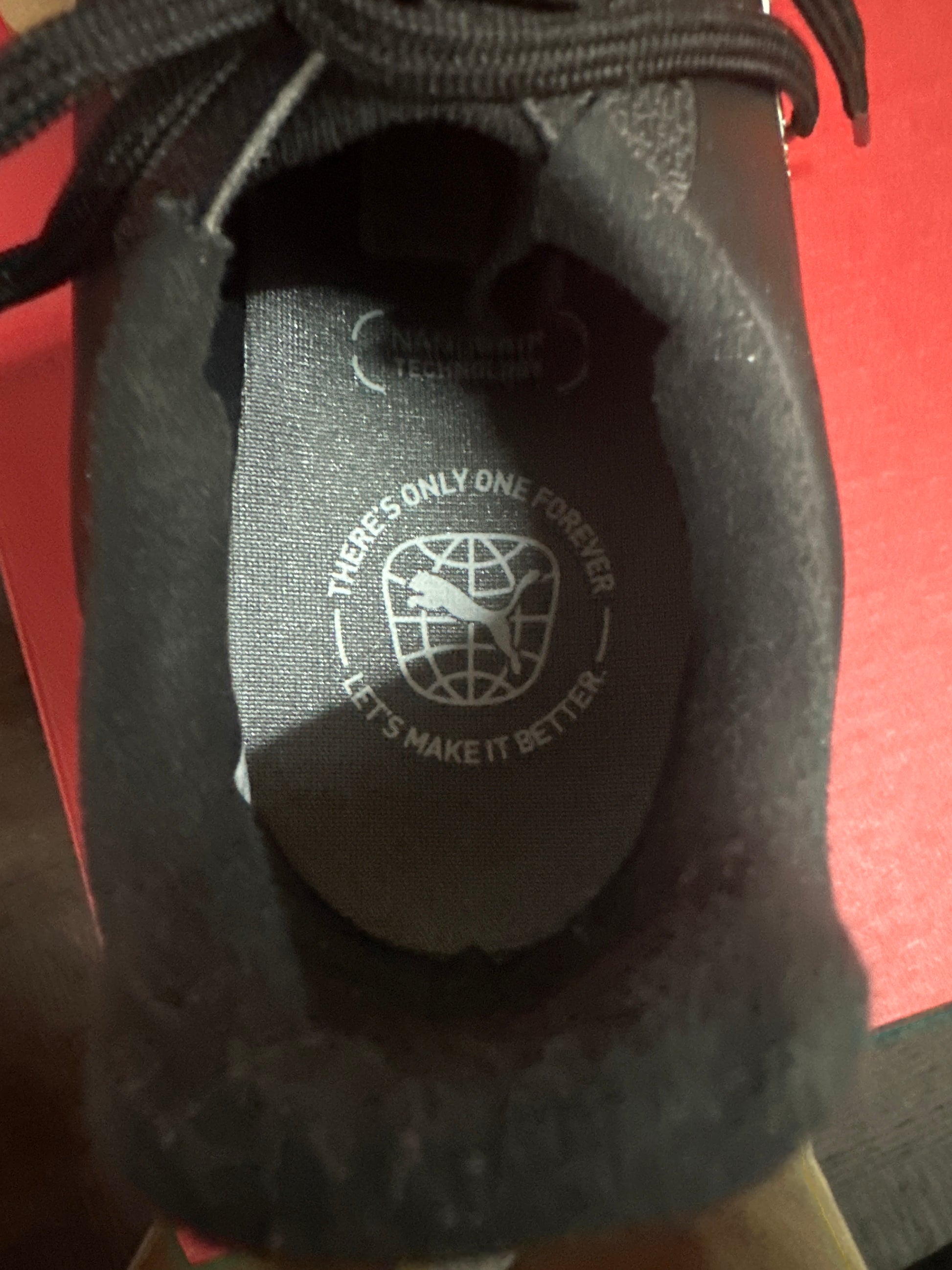 Close-up of a shoe with text and logo on the insole against a red background