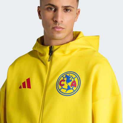 Man wearing a yellow jacket with Adidas and Club América logos on a light gray background