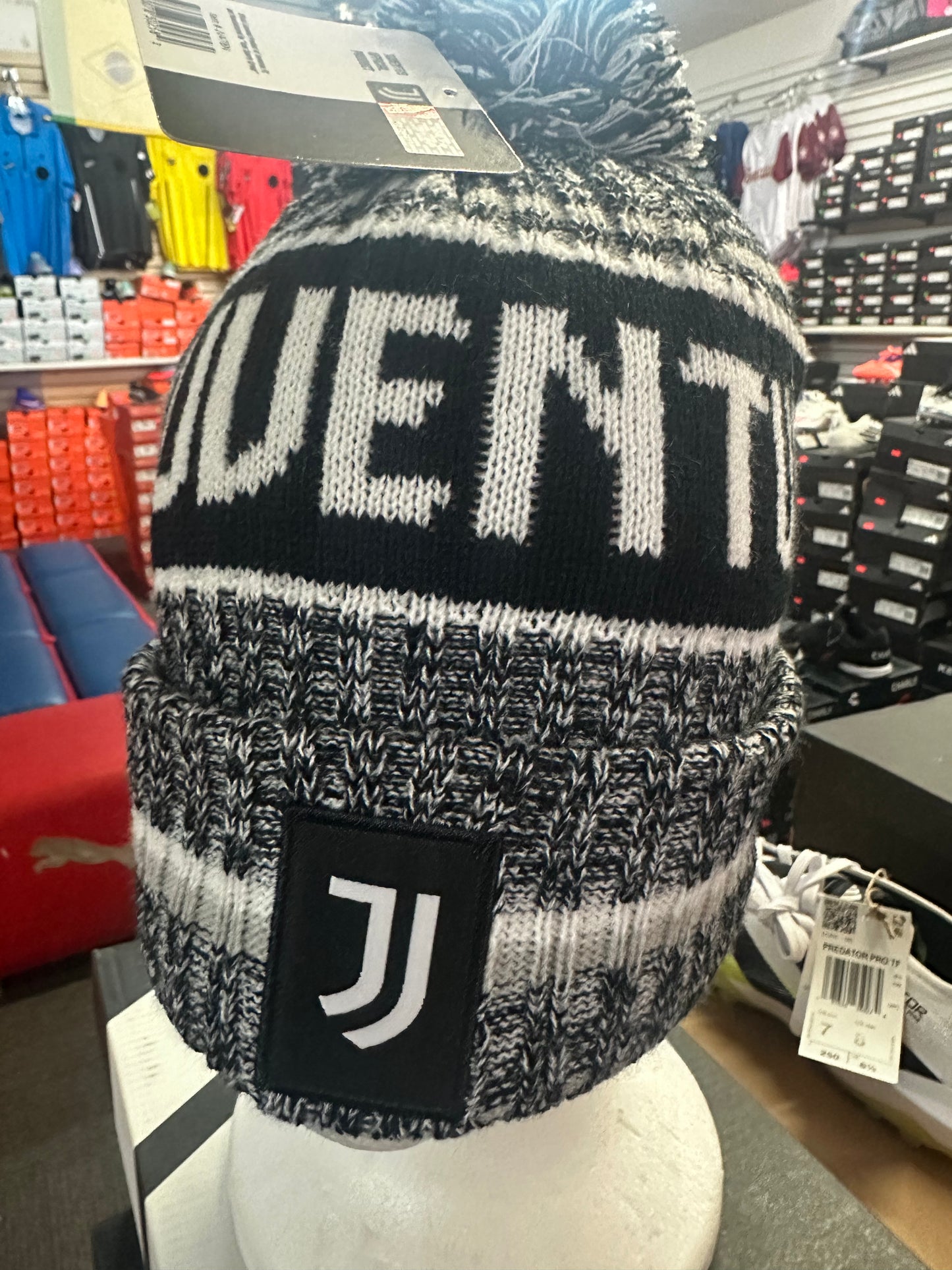 Black and gray knit beanie with 'Juventus' branding on a mannequin head in a store setting.