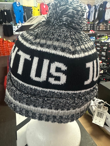 Black and gray knit beanie with 'TUS' text on a mannequin head in a store setting.