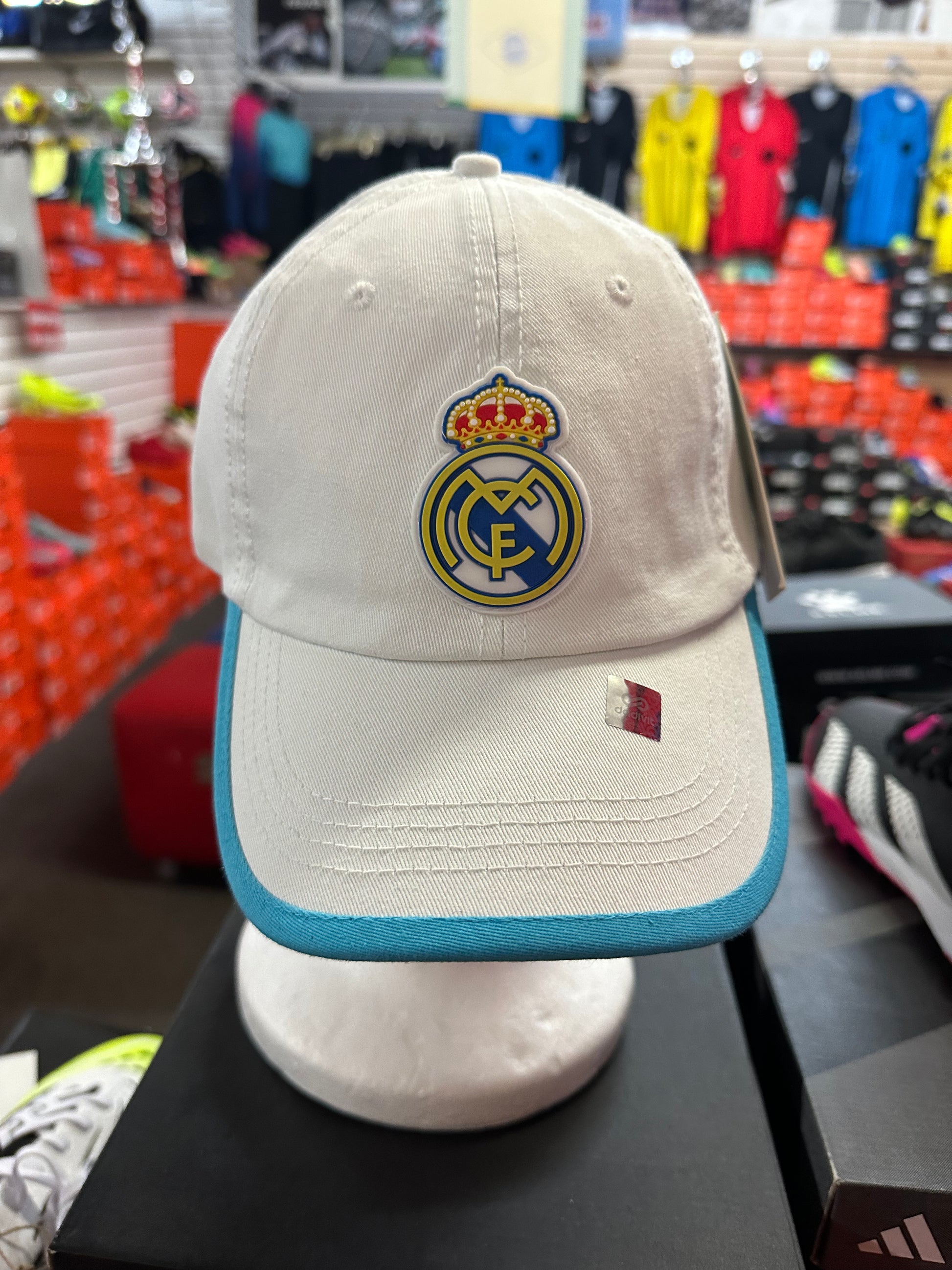 white cap with Real Madrid logo on a mannequin in a store setting