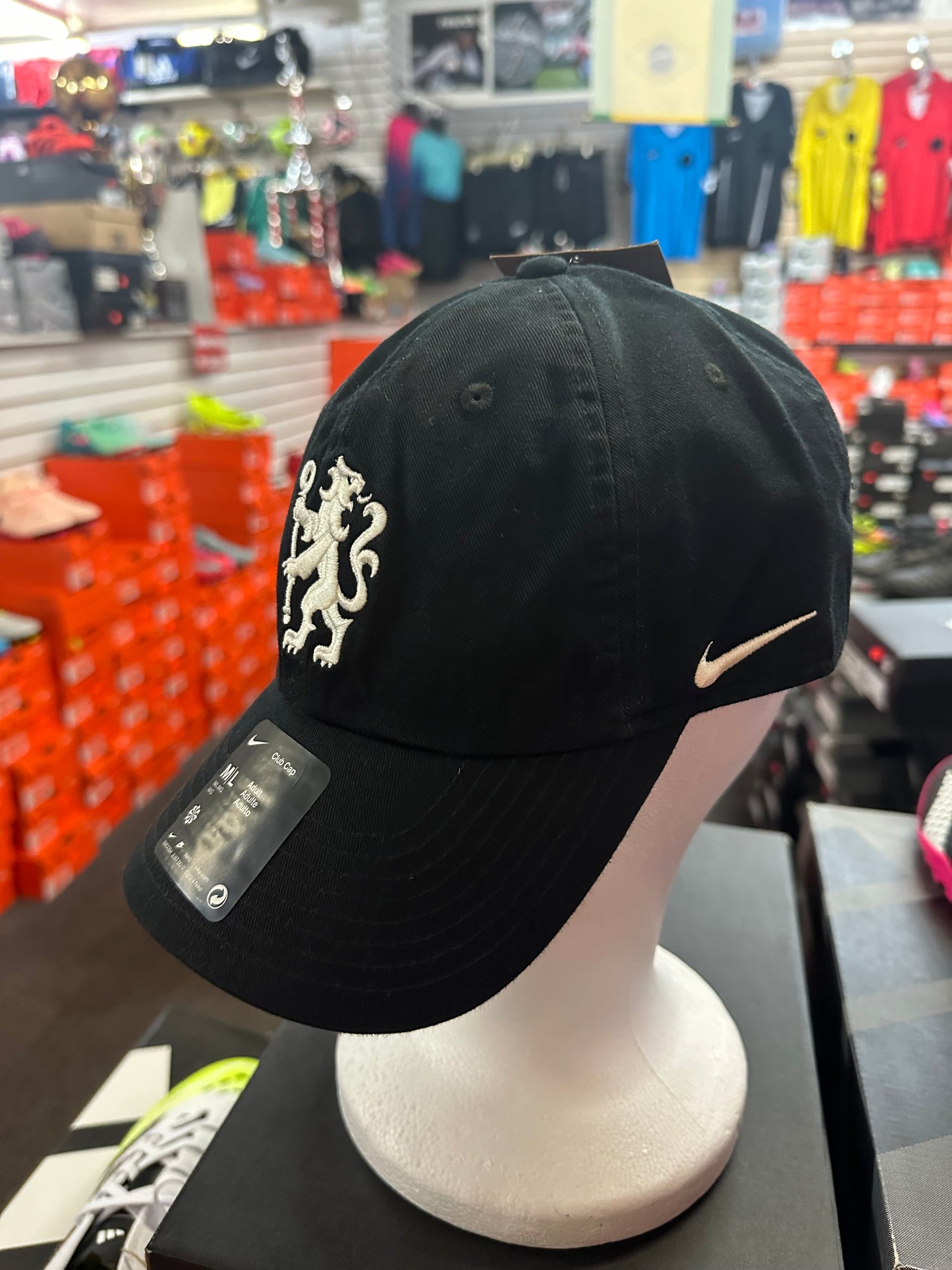 Black cap with a logo on a mannequin head in a store setting