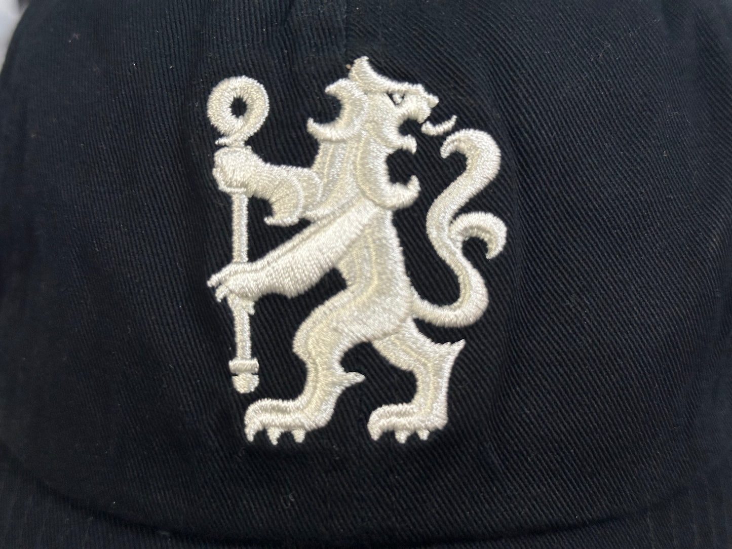 Black cap with a white embroidered lion emblem on a dark background