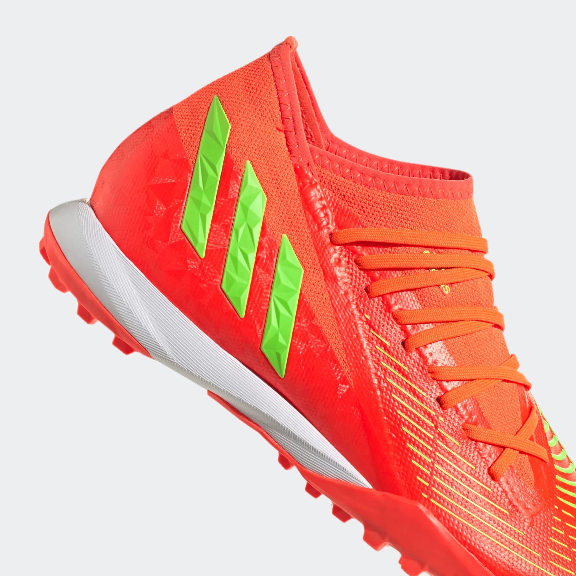 Orange soccer shoe with green accents on a light gray background