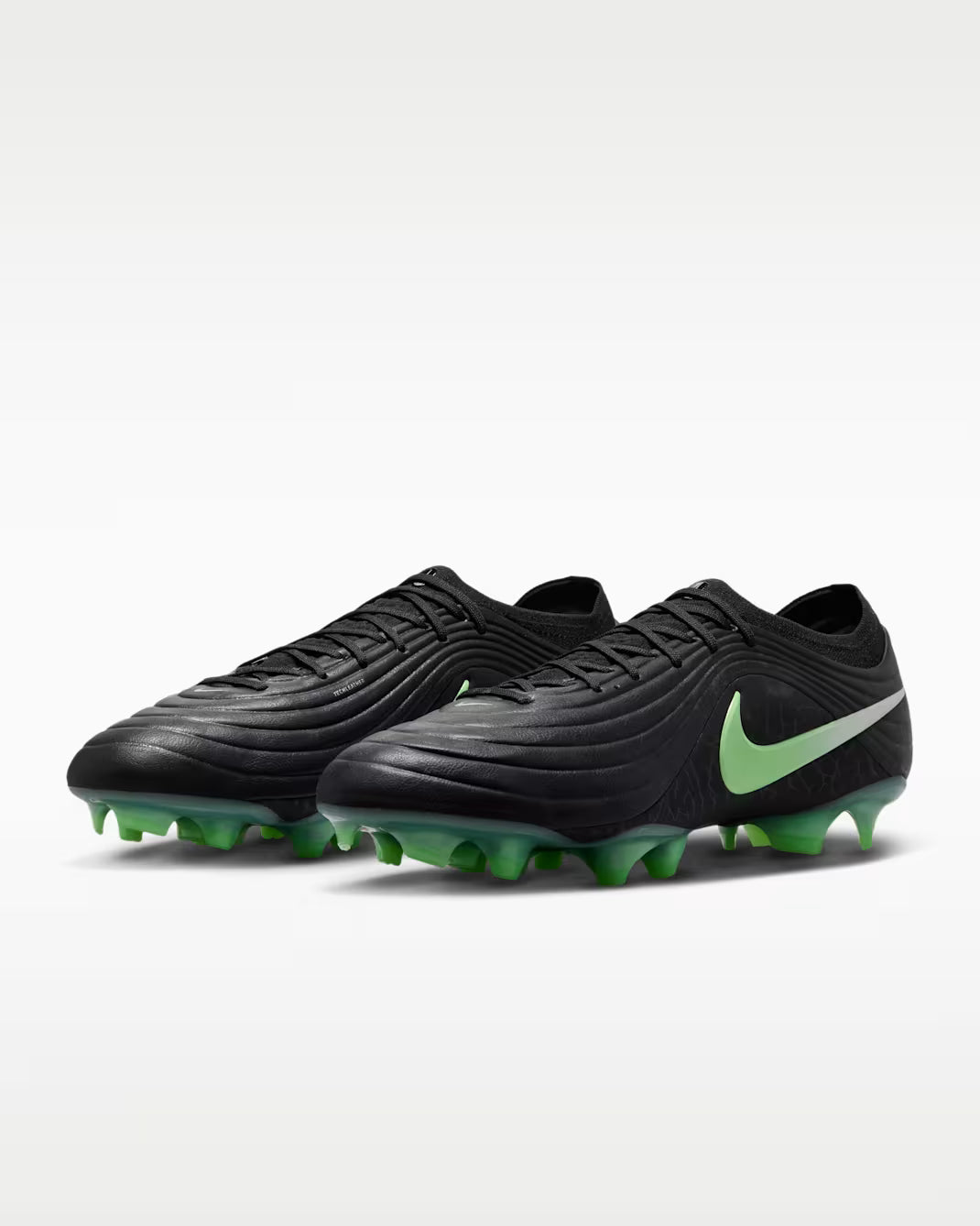 Black soccer cleats with green accents on a white background
