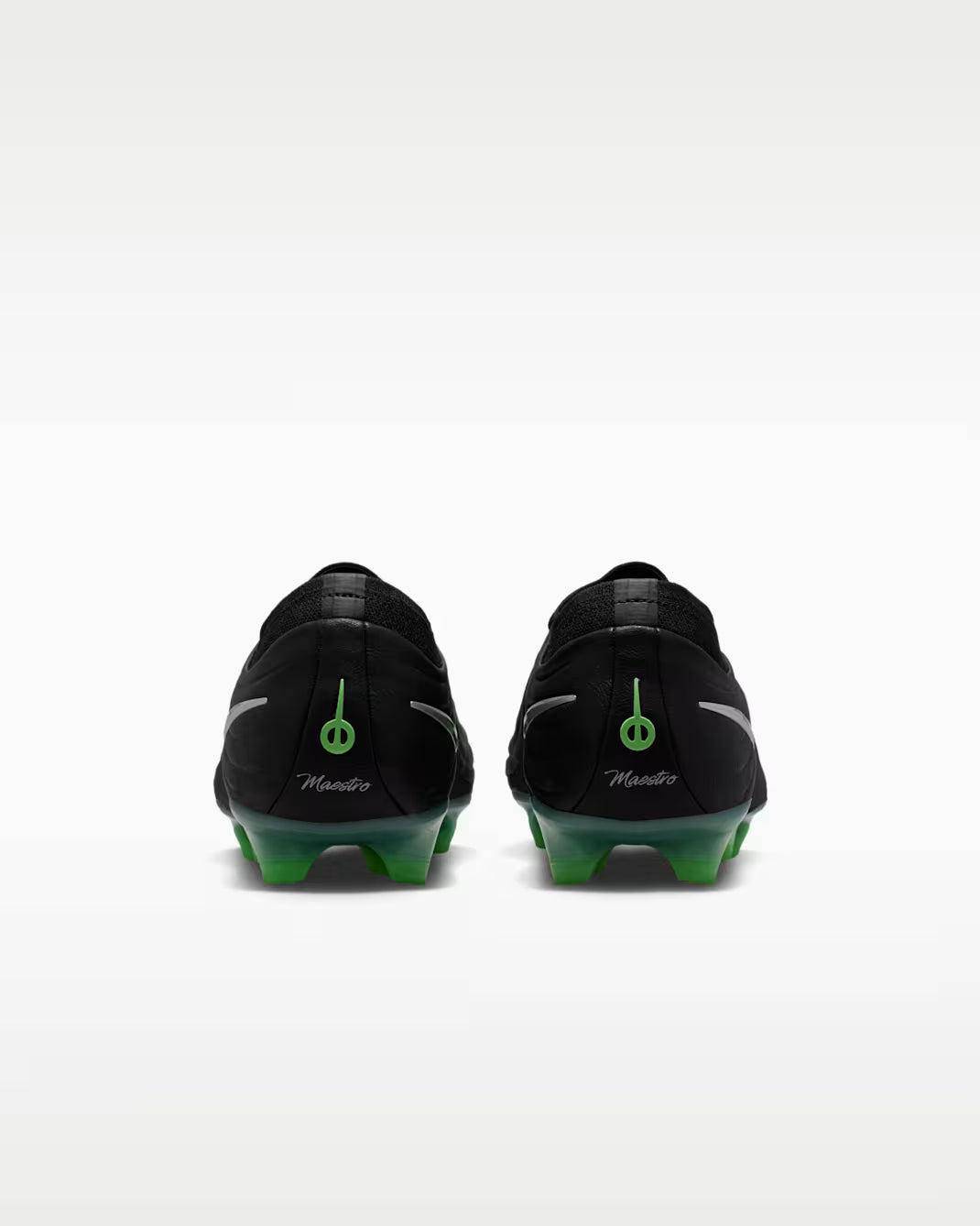 Black soccer cleats with green accents on a white background