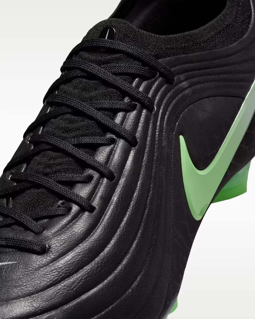 Black soccer cleat with green Nike logo on a light gray background
