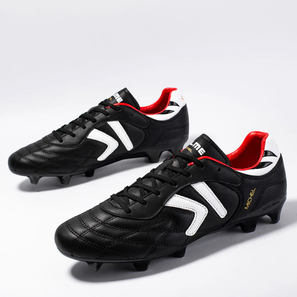 Kelme Black soccer cleats with red and white accents on a light gray background